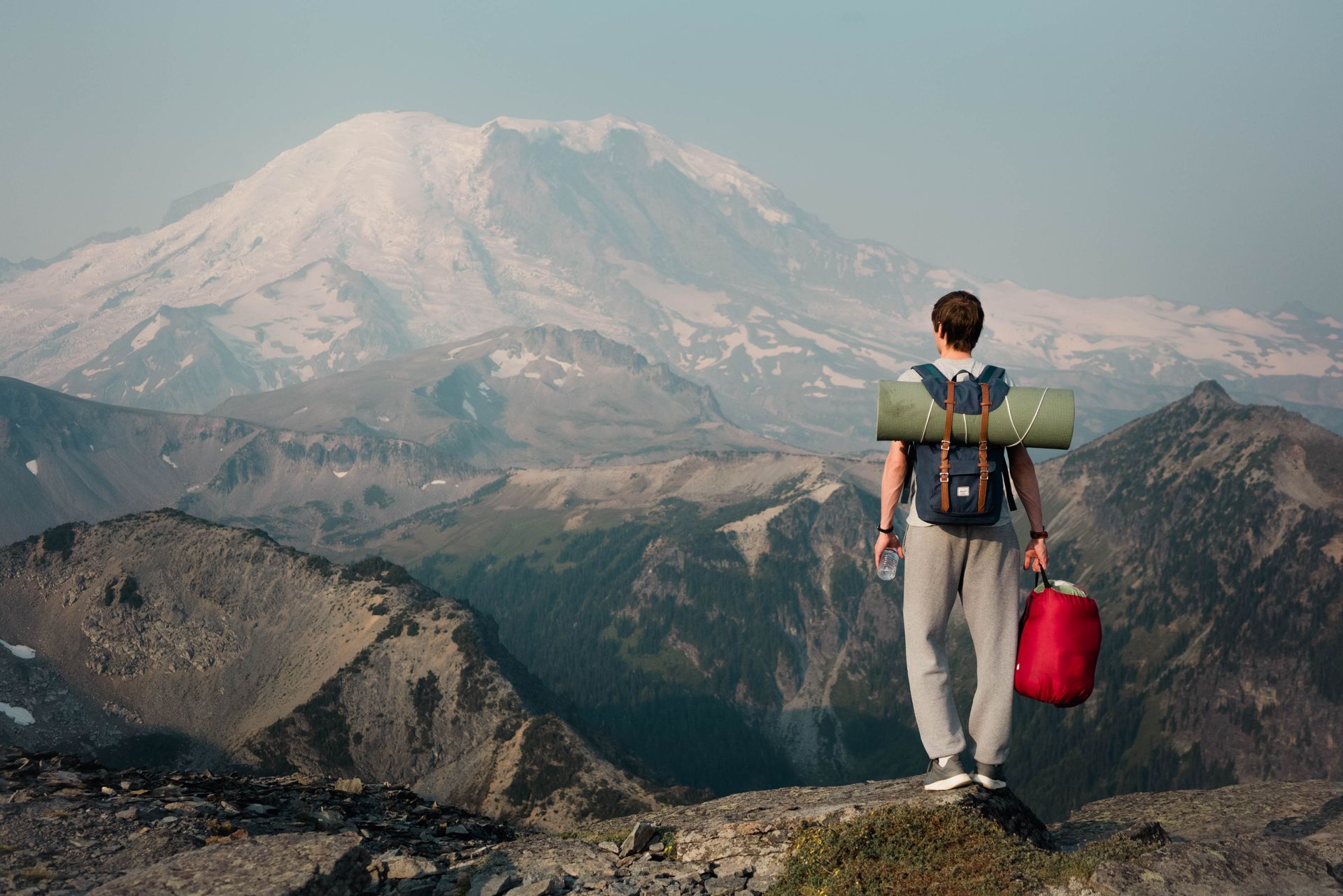 Traveller sitting on a rock above a wide mountain valley
